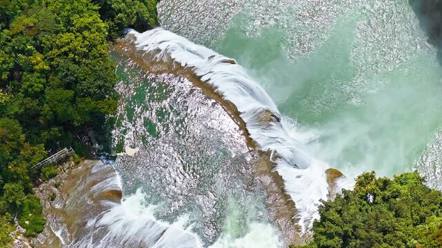 The famous Huangguoshu Waterfall natural landscape in Guizhou, China. Aerial shot of a magnificent large waterfall cascading down into a turquoise pool surrounded by lush green tropical forest in summ
