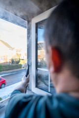 Cleaning the window. A man with steam device removes dirt from the plastic window frame.