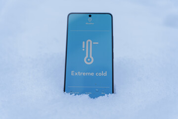 Smartphone screen showing low temperature thermometer lying in snow outdoors, extreme cold concept