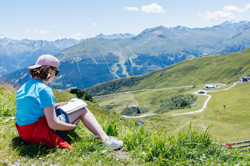 Young girl reading a book enjoying the mountain view in summer © Elena Medoks