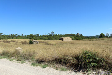 Fototapeta premium Empty field with rural houses along the route from Montserrat to Manresa in Catalonia, Spain, taken in July 2024.