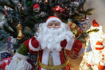 A Santa Claus toy on the background of a Christmas tree.