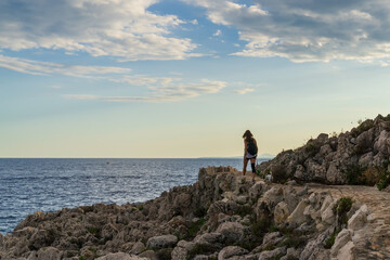 Obraz premium Young woman hiking with her dog along the rocky coastal path of Saint-Jean-Cap-Ferrat overlooking the Mediterranean Sea in France.