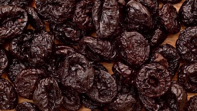 Pile of dried plums or prunes on the wooden table. Close-up. Top view.