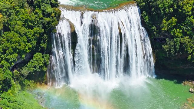 The famous Huangguoshu Waterfall natural landscape in Guizhou, China. Aerial shot of a magnificent large waterfall cascading down into a turquoise pool surrounded by lush green tropical forest in summ