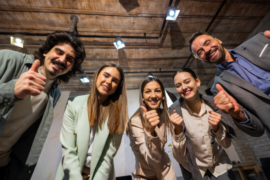 Group of young business professionals in an office looking down at the camera and posing