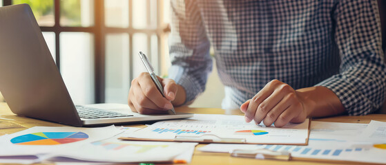 A professional working at an office desk reviewing financial documents and charts, focusing on analysis, planning, and business strategy in a modern workspace.