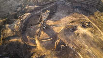 High resolution panoramic view of massive mining machines in an open pit coal mine, surrounded by dust. Powerful industrial scene showing large scale extraction, energy production, and human impact.
