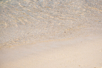 Soft sea wave on sandy beach crystal clear water ripple on pristine sand beach.Summer beach background with water wave and golden sand
