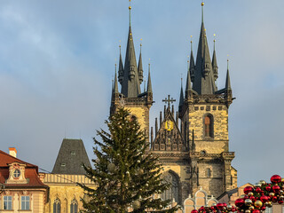 Fototapeta premium The Gothic twin spires of the Church of Our Lady before Týn rise majestically behind a decorated Christmas tree in the Old Town Square of Prague, Czechia, capturing the festive spirit of winter.