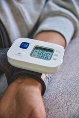 Person monitoring heart health and pulse using a digital blood pressure cuff on the wrist