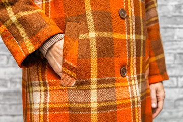 The woman put her hand in her coat pocket, close-up. hand in coat pocket. fragment of a checkered coat. 