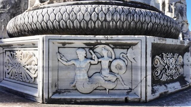 A detailed marble relief carving on an ornate column base at the ancient Apollo Temple ruins in Didyma, Turkey.