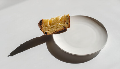 Delicate Panettone slice hovering above pristine ceramic bowl in contemporary minimalist food styling composition