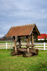 Wooden animal feeder with a tiled roof on a farm.