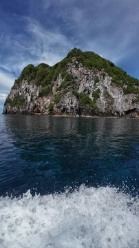 A dramatic view of a green-clad tropical island&acirc;&euro;&trade;s cliffs seen from the open sea in Suanggi, Banda Sea, Maluku, Indonesia.