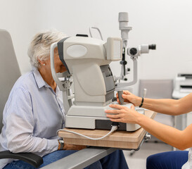 Female doctor's hands controlling slit lamp while performing senior woman eye examination in medical clinic