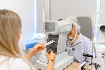 Female ophthalmologist checking slit lamp results while examining senior woman eyes during vision assessment