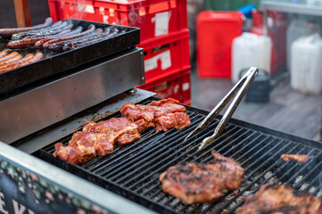 Close up view of grill at christmas market stall with sausages and meat cooking over hot coals, street food scene with smoke, heat and traditional winter festive atmosphere
