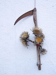 Rusty, wooden handle with a curved blade hanging from a white wall