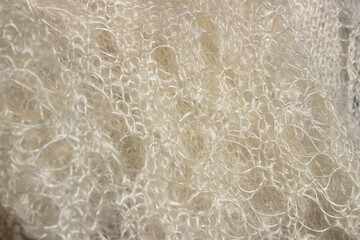 White mohair wool knitted texture in a close-up view, soft fluffy handicraft background captured in natural light for cozy winter concept © Lilu