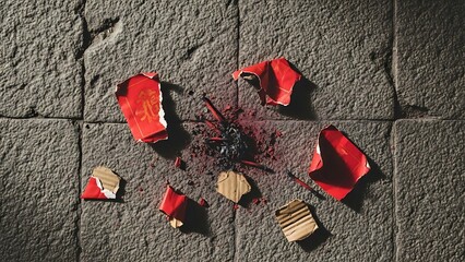 Burnt red envelopes scattered on stone floor with Chinese characters