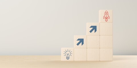 Rising stacks of wooden blocks with arrows from idea light bulb to start up rocket icon, startup, innovation or business invention concept