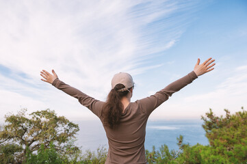 Woman celebrates freedom and success overlooking ocean horizon