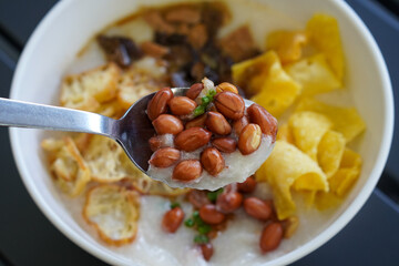Chicken and mushroom rice porridge with creamy smooth texture, savory toppings, crunchy crackers, peanuts, herbs, and warm comforting flavor, modern Asian breakfast dish with clean appetizing presenta
