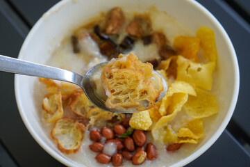 Chicken and mushroom rice porridge with creamy smooth texture, savory toppings, crunchy crackers, peanuts, herbs, and warm comforting flavor, modern Asian breakfast dish with clean appetizing presenta
