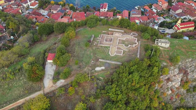 Aerial video of Lin village on Lake Ohrid, showing terracotta rooftops, turquoise water, and the ancient basilica ruins on the peninsula.