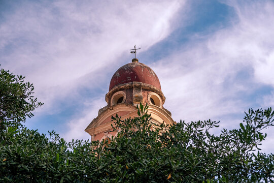 Church bell tower with a red dome above lush greenery in Corfu, Greece.  Monastery of Tenedos at old town.