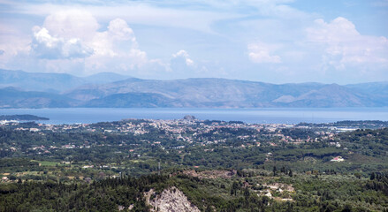 Panoramic view of Corfu town from Pelekas hill, lush green valleys, the Ionian Sea and distant Albanian mountains, Greece