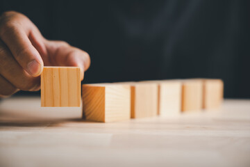 A conceptual sign of strategy, this closeup shows a man hand posing a gesture with a blank wooden block, a symbolic sign for building a new business foundation or plan.