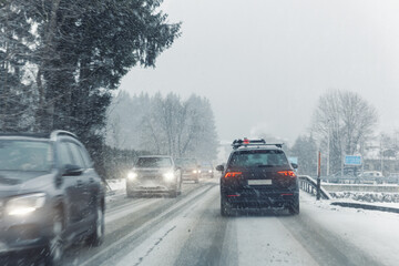 Scenic view snow covered city highway slippery mountain alpine road drive cars moving fast speed motion. Snowfall danger blizzard bad winter weather conditions. Cold snowy day snowstorm background