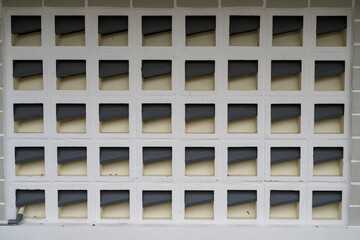 Geometric ventilation block wall pattern on a white building facade.Repetitive architectural grid texture with neutral tones,for background, construction,urban design,and exterior architecture concept