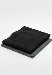 Folded Black Compression Shorts or Activewear Lying on Slate Tile Against White Background mockup