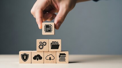 Hand placing a wooden block with a database icon on top of a stack of blocks with various business and technology icons on a table