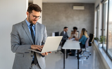Young businessman using laptop computer in office. Manager thinks about successful financial ideas
