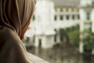 Muslim Girl Blowing Bubble Gum in Rainy Urban Scene