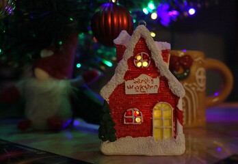 Toy, magic house, red, glowing, on the background of a Christmas tree