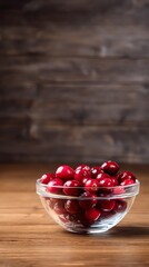A clear glass bowl filled with bright red cranberries, set against a warm wooden backdrop, creating a cozy, inviting atmosphere.