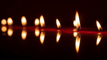 Candle lights reflecting on water surface in dark background