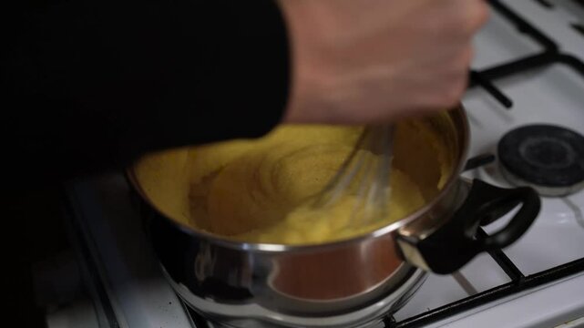 Caucasian man cooking , stir up polenta , making dinner.