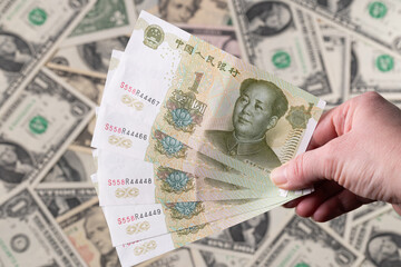 Hand Holding Chinese Yuan Over US Dollar Background