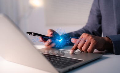 Hand of a man using mobile phone and laptop, secure access to user personal information, secure Internet access, information security encryption. Cybersecurity internet network data privacy concepts.