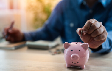 A man hand putting coins into a piggy bank for account save money. Planning step up, saving money for future plan, retirement fund. A business investment-finance accounting concept.