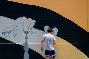 Street artist painting wall mural in urban setting