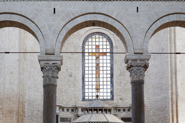 Arched columns and stained glass window with cross in historic church
