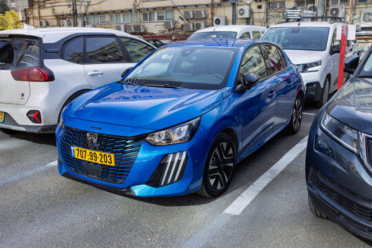 Front view of a blue Peugeot e-208 facelift electric hatchback parked in a city lot, Ramat Gan, Israel, 24 December, 2025